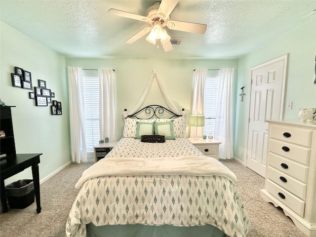 carpeted bedroom featuring multiple windows, ceiling fan, and a textured ceiling