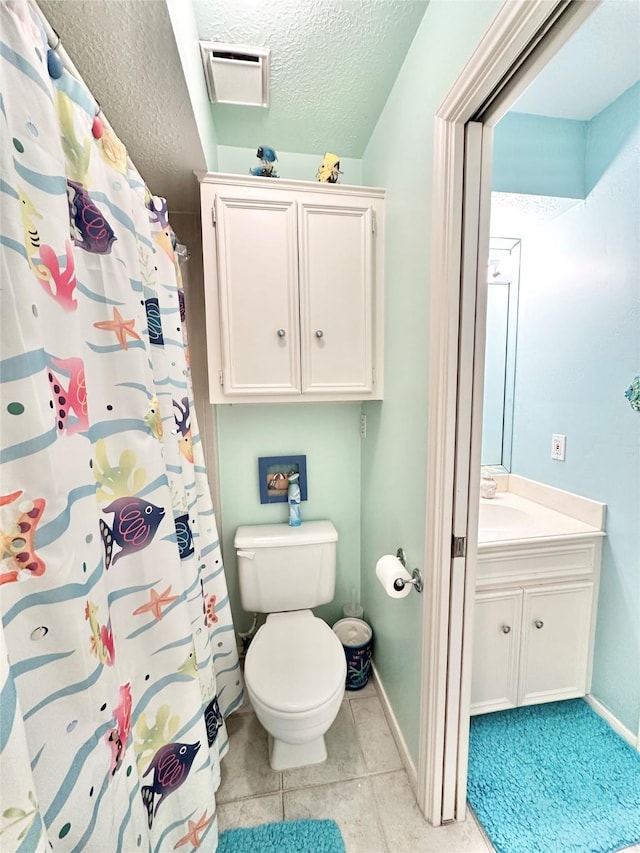 bathroom featuring tile patterned flooring, vanity, toilet, and a textured ceiling