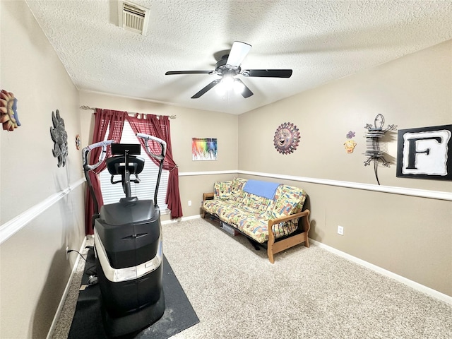 exercise room with ceiling fan, carpet floors, and a textured ceiling