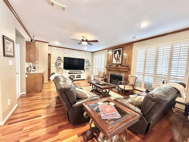 living room with a textured ceiling, light hardwood / wood-style flooring, ceiling fan, and crown molding