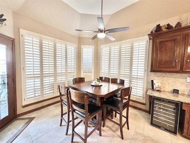 tiled dining space featuring ceiling fan, wine cooler, and vaulted ceiling