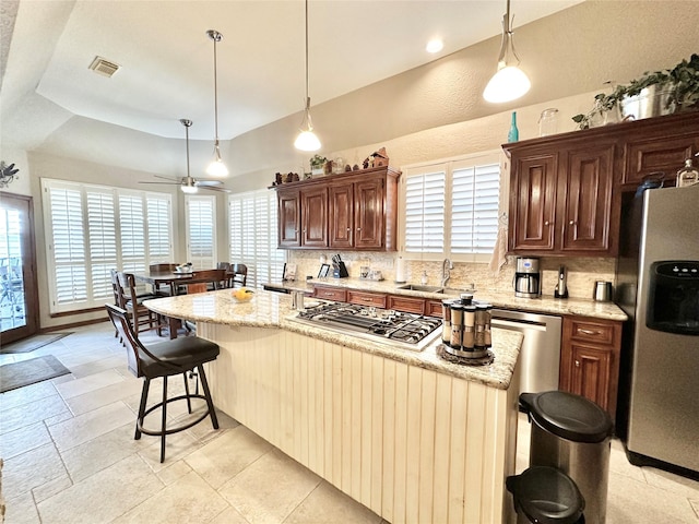 kitchen featuring light stone counters, a kitchen island, and appliances with stainless steel finishes