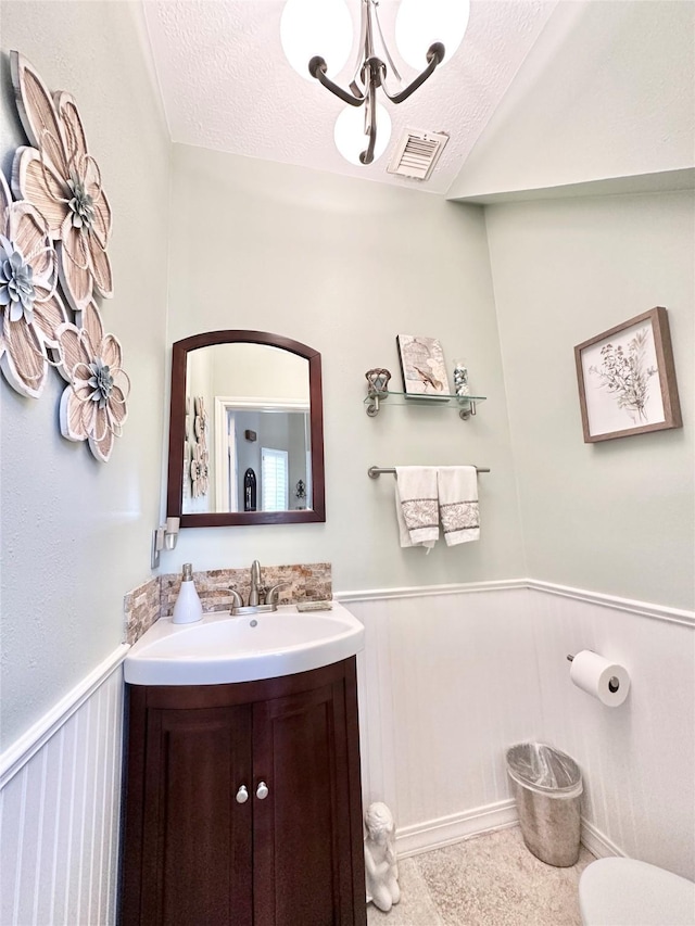 bathroom with a notable chandelier, vanity, and a textured ceiling