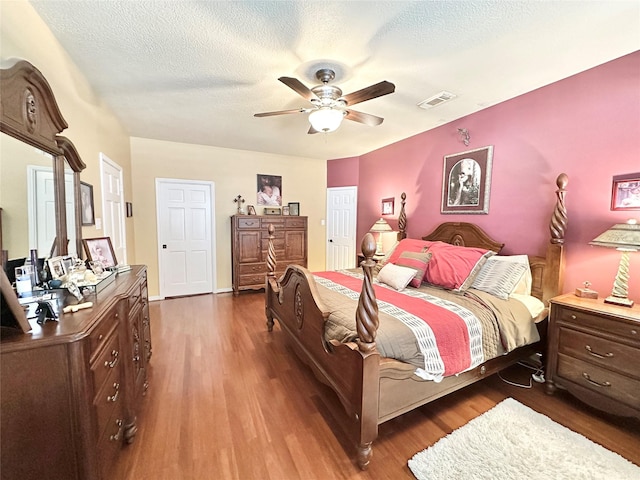 bedroom featuring ceiling fan, dark hardwood / wood-style flooring, and a textured ceiling