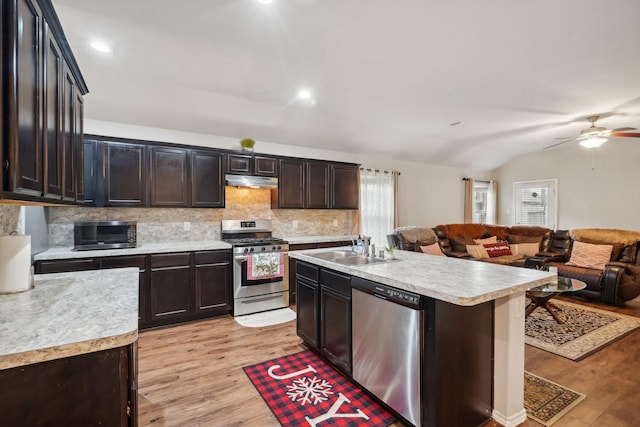 kitchen with an island with sink, stainless steel appliances, light hardwood / wood-style floors, and sink