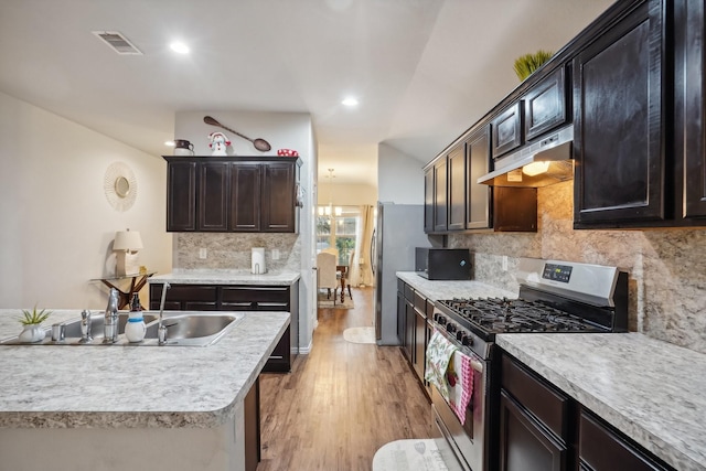 kitchen featuring sink, backsplash, light hardwood / wood-style floors, dark brown cabinets, and stainless steel range with gas stovetop