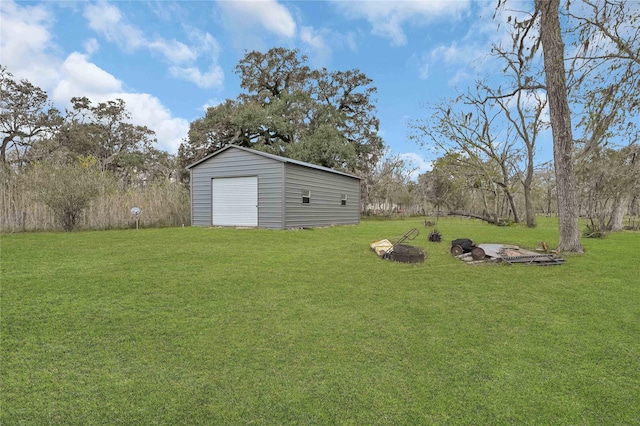 view of yard featuring an outbuilding, a garage, and a fire pit