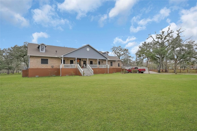 rear view of property featuring covered porch and a yard