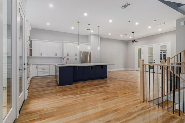 kitchen with hanging light fixtures, a center island with sink, white cabinetry, high end fridge, and ceiling fan