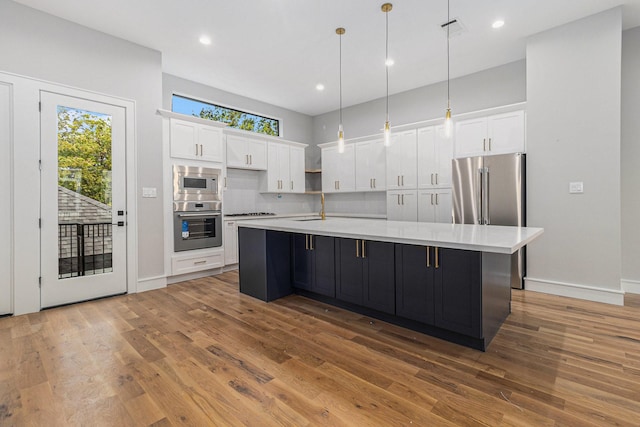 kitchen with sink, decorative light fixtures, a large island, white cabinets, and appliances with stainless steel finishes