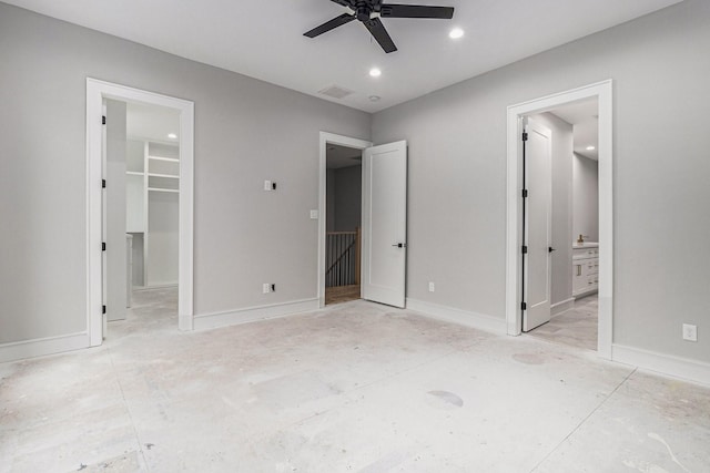 unfurnished bedroom featuring ceiling fan, a spacious closet, ensuite bathroom, and a closet