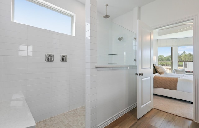 bathroom with hardwood / wood-style flooring, tiled shower, and a wealth of natural light