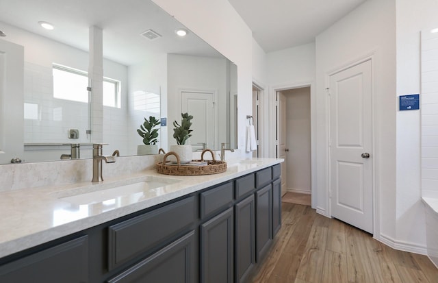 bathroom featuring hardwood / wood-style flooring, vanity, and a shower