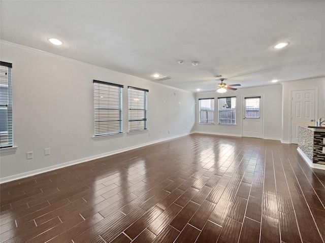 unfurnished living room featuring dark hardwood / wood-style floors, ceiling fan, a stone fireplace, and ornamental molding