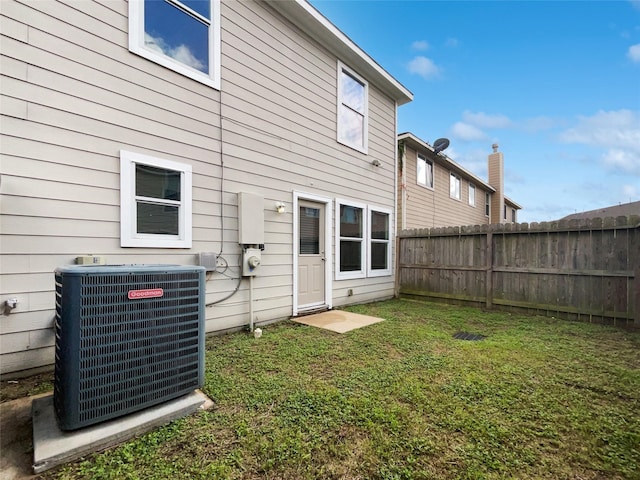 rear view of property with a lawn and central air condition unit