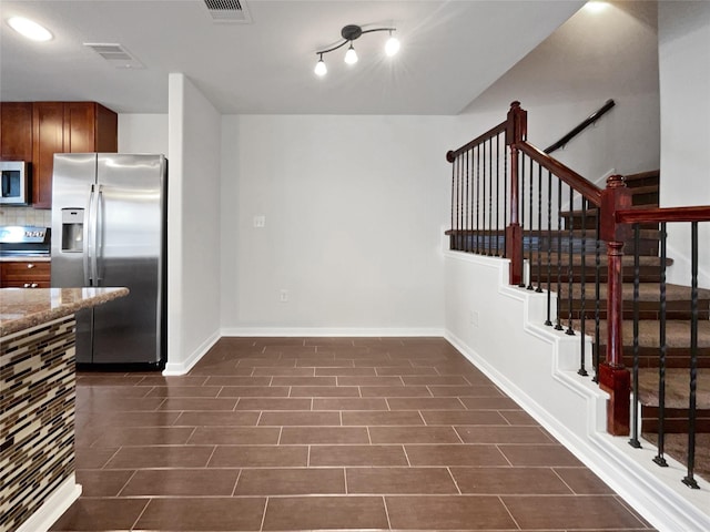 kitchen featuring appliances with stainless steel finishes, backsplash, and stone countertops