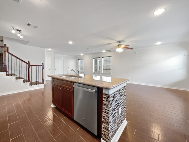 kitchen with dark wood-type flooring, a center island with sink, sink, stainless steel dishwasher, and ceiling fan