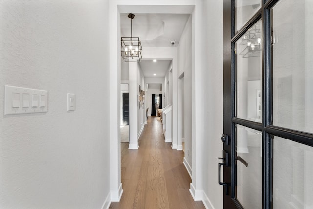 corridor with hardwood / wood-style floors and a notable chandelier