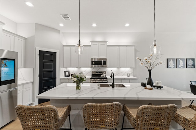 kitchen with an island with sink, decorative light fixtures, and appliances with stainless steel finishes