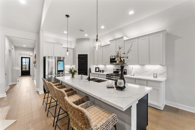 kitchen featuring a center island with sink, a kitchen breakfast bar, light hardwood / wood-style floors, and stainless steel appliances