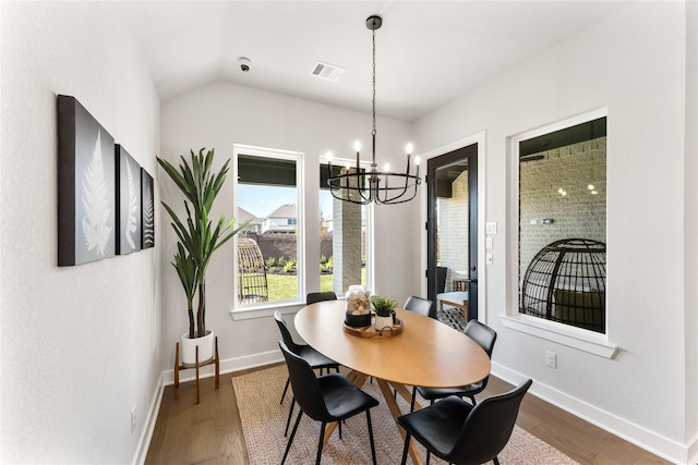 dining space featuring a notable chandelier, dark hardwood / wood-style floors, and vaulted ceiling