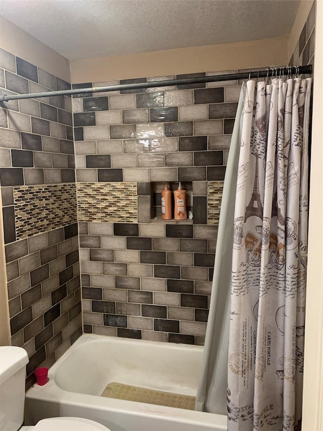 bathroom with a textured ceiling, toilet, and shower / bath combo with shower curtain