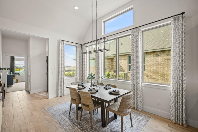 dining room featuring a notable chandelier, vaulted ceiling, and light hardwood / wood-style flooring