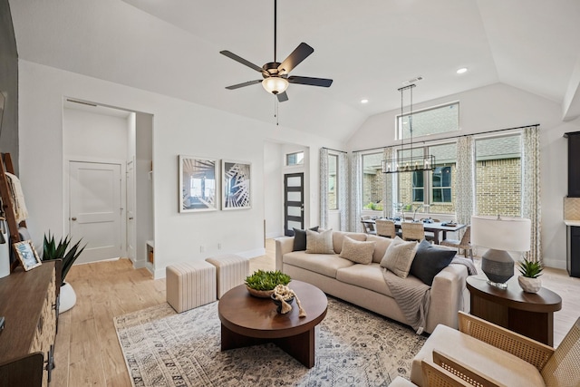 living room with ceiling fan, light hardwood / wood-style flooring, and vaulted ceiling