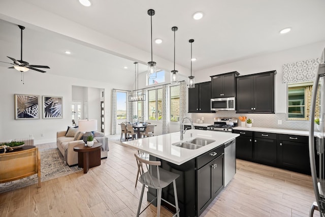 kitchen with pendant lighting, a breakfast bar, a kitchen island with sink, sink, and stainless steel appliances