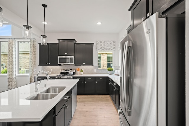 kitchen with stainless steel appliances, a kitchen island with sink, a wealth of natural light, and sink