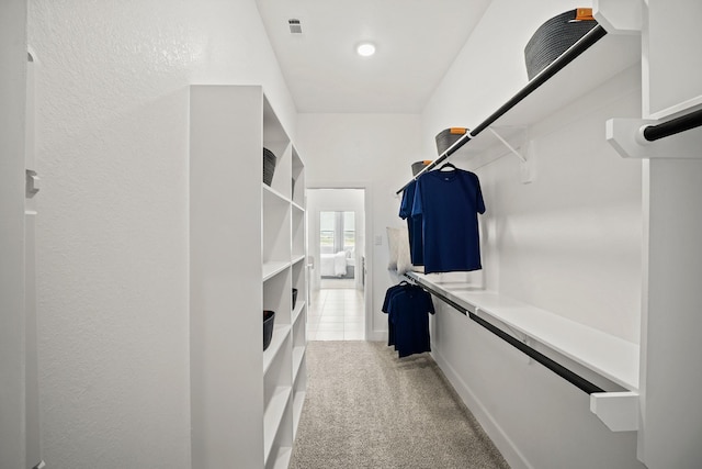 walk in closet with light colored carpet