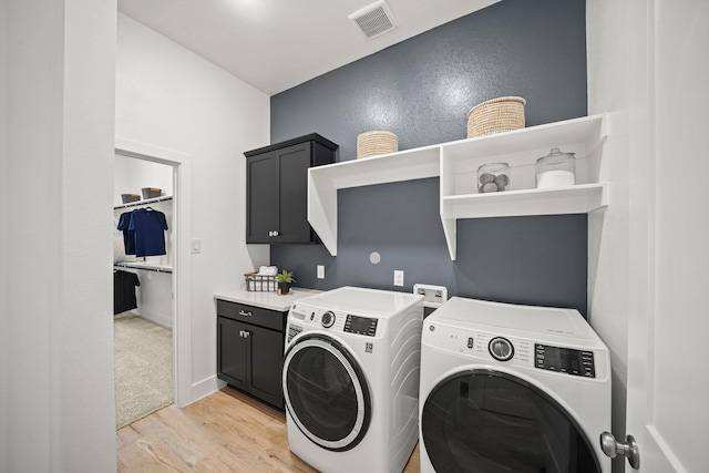 washroom with cabinets, light wood-type flooring, and washing machine and clothes dryer