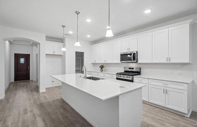 kitchen featuring sink, white cabinetry, a kitchen island with sink, hanging light fixtures, and stainless steel appliances