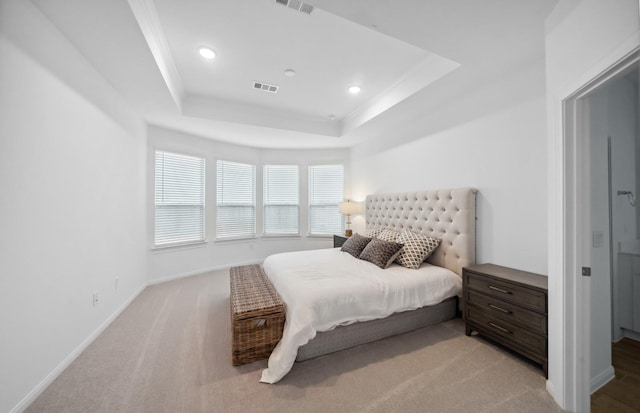 bedroom with light colored carpet, ornamental molding, and a tray ceiling