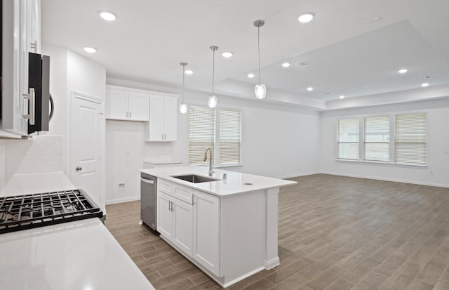 kitchen with sink, dishwasher, a kitchen island with sink, white cabinetry, and a raised ceiling