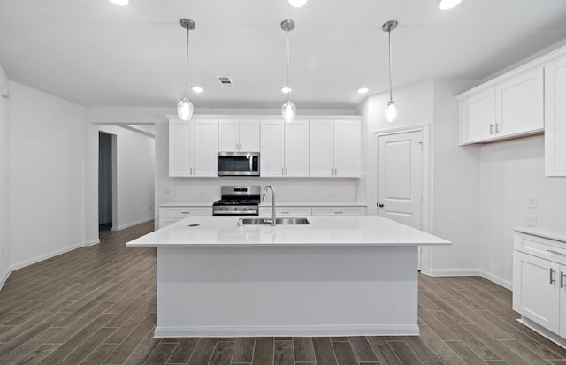 kitchen with pendant lighting, sink, a kitchen island with sink, and stainless steel appliances