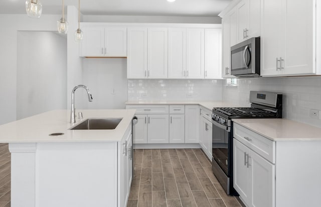 kitchen featuring a center island with sink, stainless steel appliances, a sink, and decorative light fixtures