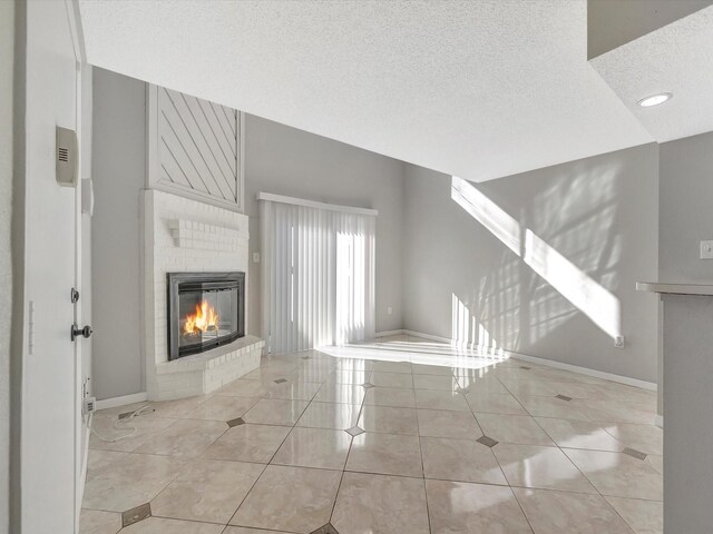 unfurnished living room featuring a fireplace, light tile patterned floors, and a textured ceiling