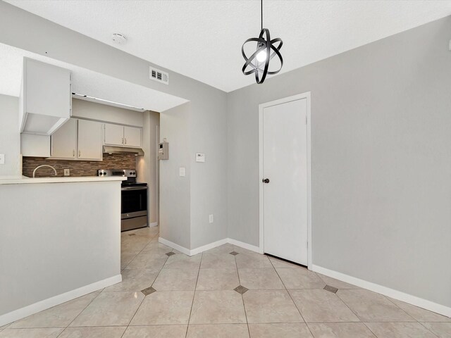 kitchen with stainless steel electric range, backsplash, hanging light fixtures, light tile patterned floors, and a textured ceiling