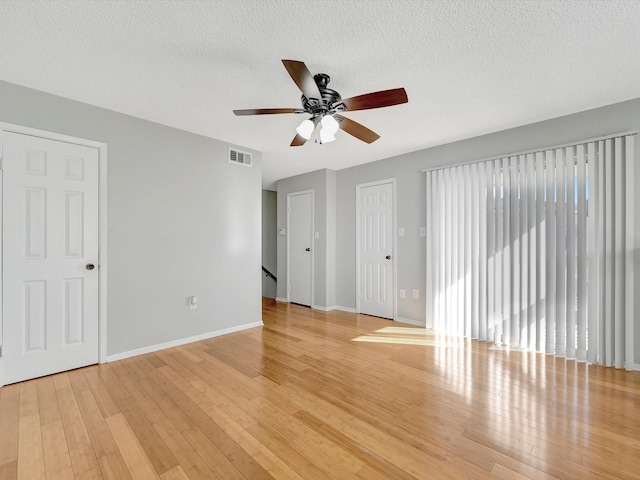 empty room featuring ceiling fan, light hardwood / wood-style floors, and a textured ceiling