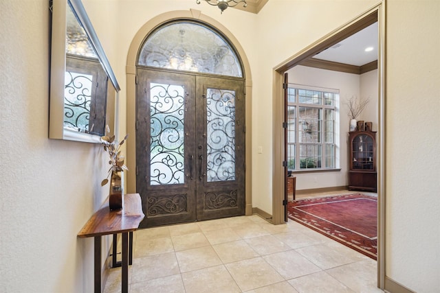 entryway featuring french doors, light tile patterned floors, and ornamental molding