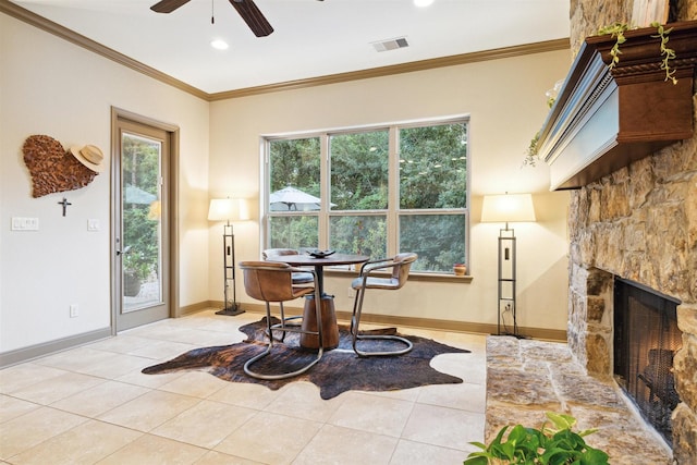 interior space featuring light tile patterned floors, a stone fireplace, ceiling fan, and crown molding