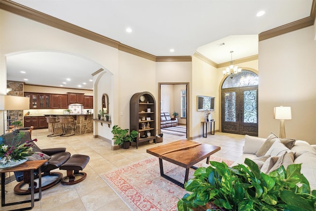 tiled living room featuring crown molding, french doors, and a chandelier