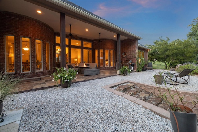 back house at dusk with outdoor lounge area, ceiling fan, and a patio area