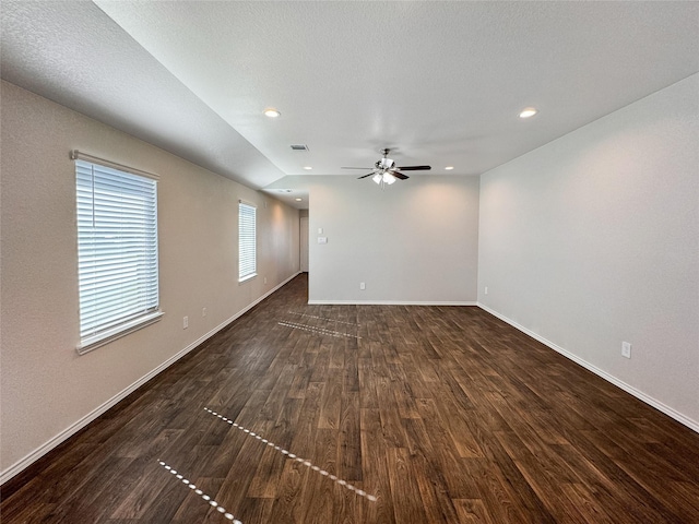 spare room with a textured ceiling, lofted ceiling, ceiling fan, and dark hardwood / wood-style floors