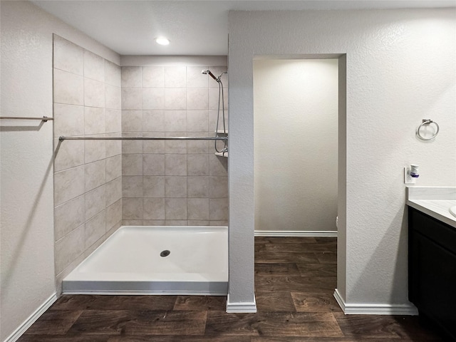 bathroom featuring hardwood / wood-style floors, vanity, and a tile shower