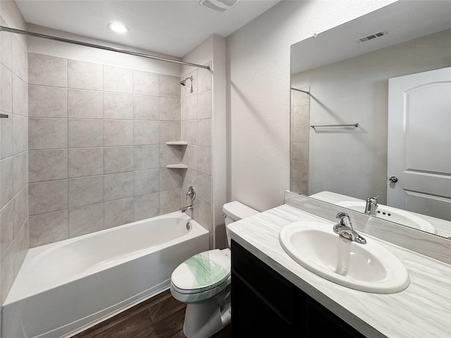 full bathroom featuring tiled shower / bath combo, toilet, wood-type flooring, and vanity