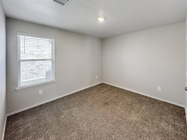 carpeted empty room featuring a textured ceiling