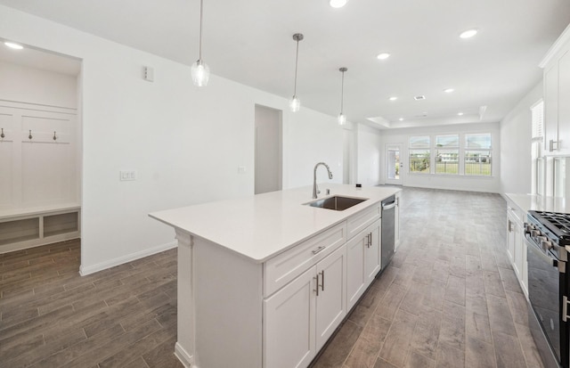 kitchen featuring white cabinets, an island with sink, appliances with stainless steel finishes, light countertops, and a sink