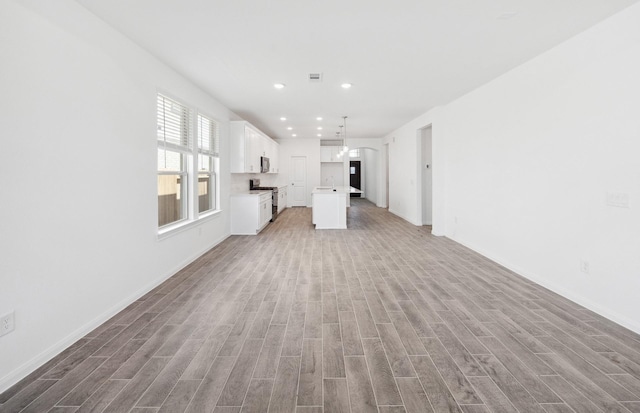 unfurnished living room featuring a sink, a notable chandelier, wood finished floors, and recessed lighting